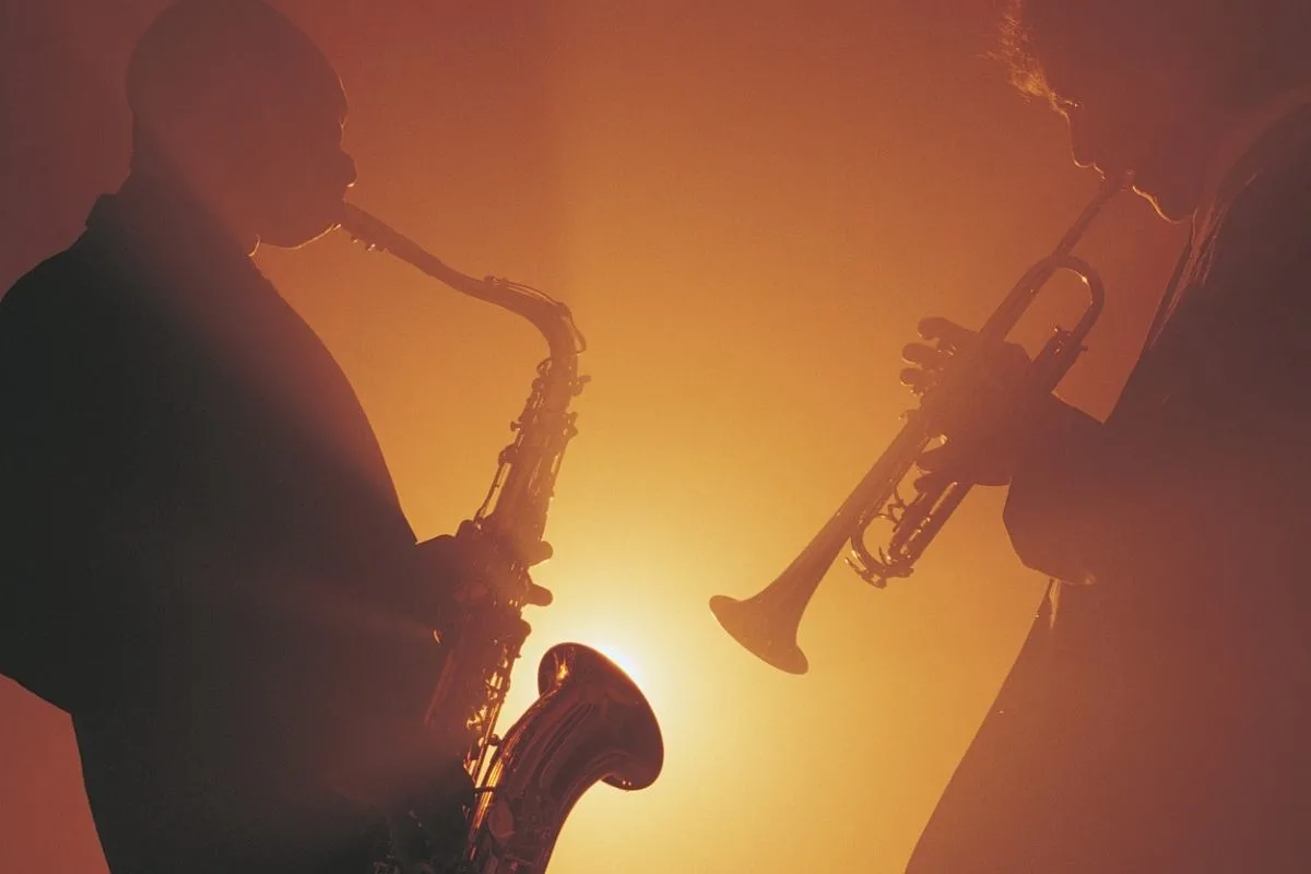 two male musicians playing the trumpet and saxophone at a concert