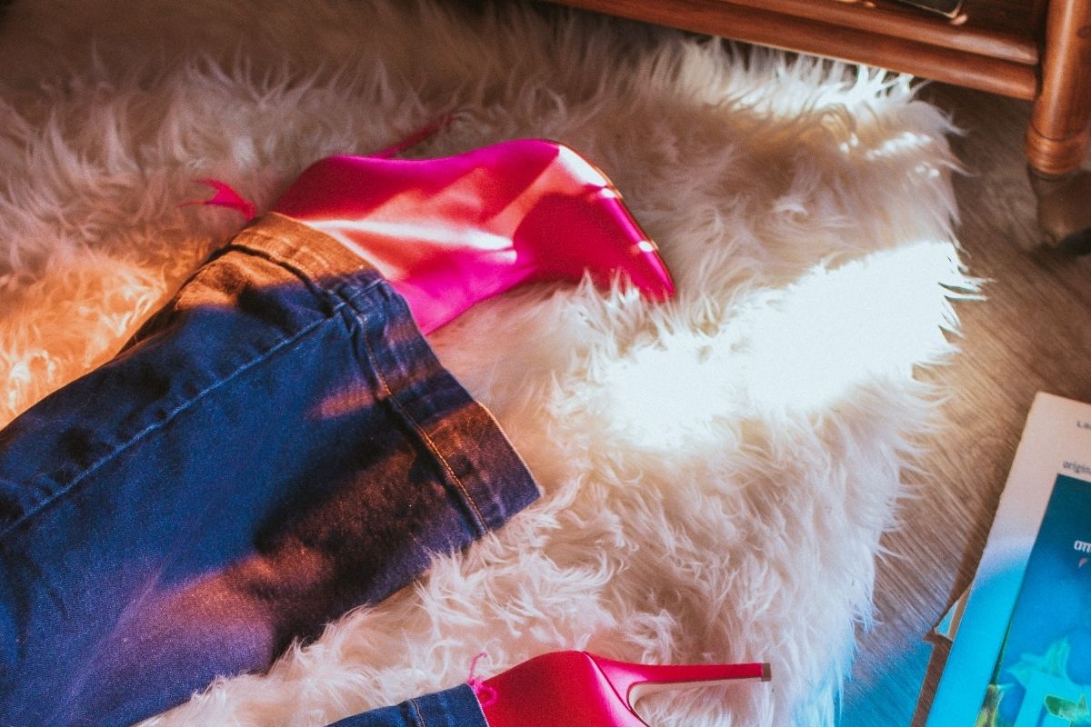 woman wearing 70s style jeans and heels on a white faux fur rug