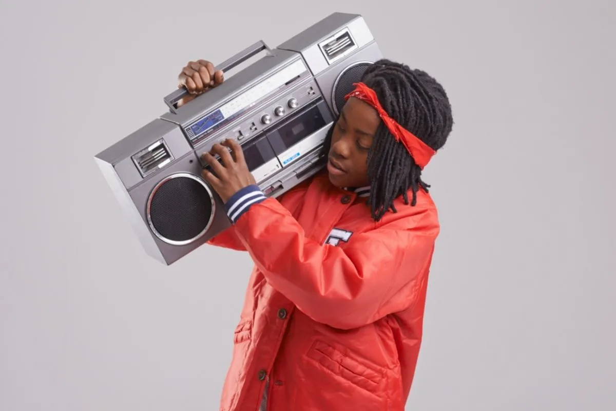 young African American man holding an 80's style boom box