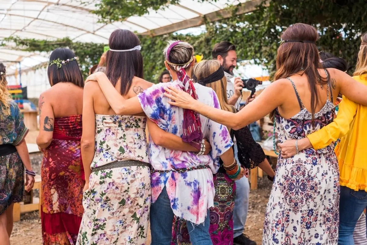 multiple young adults walking with arms around each other at a hippie festival