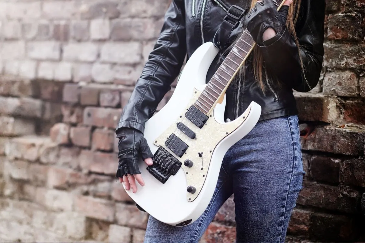 photo of a rocker in a leather jacket and blue jeans holding an electric guitar