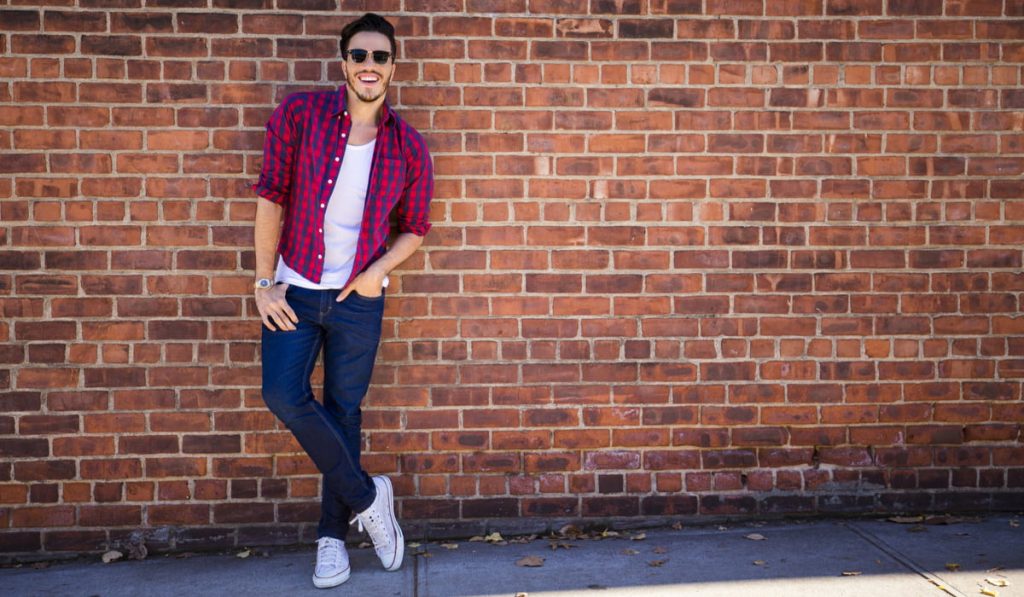 young man wearing checked polo, skinny jeans and converse shoes