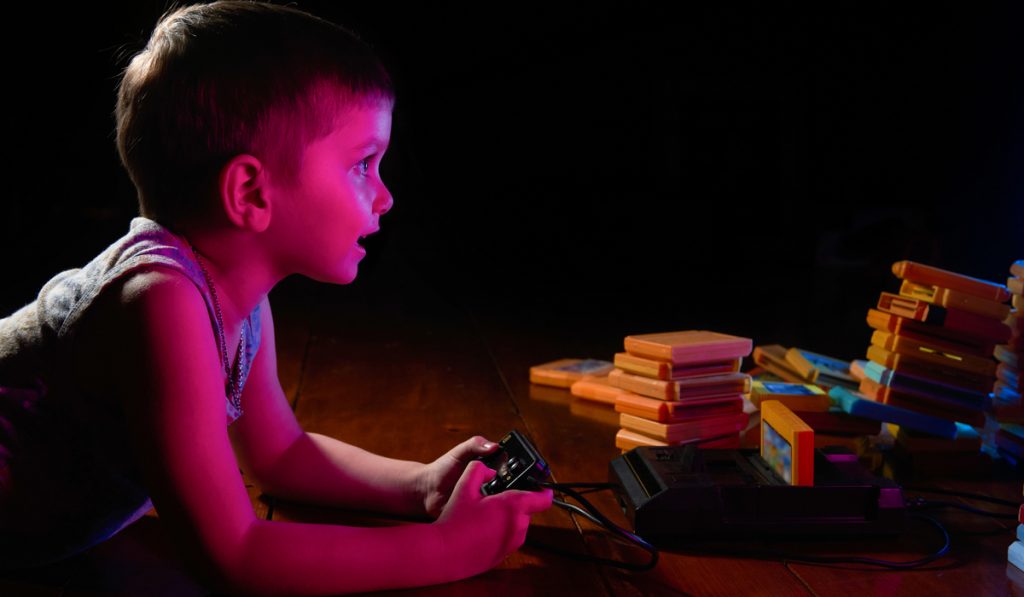 Little boy playing an old video game on a retro console