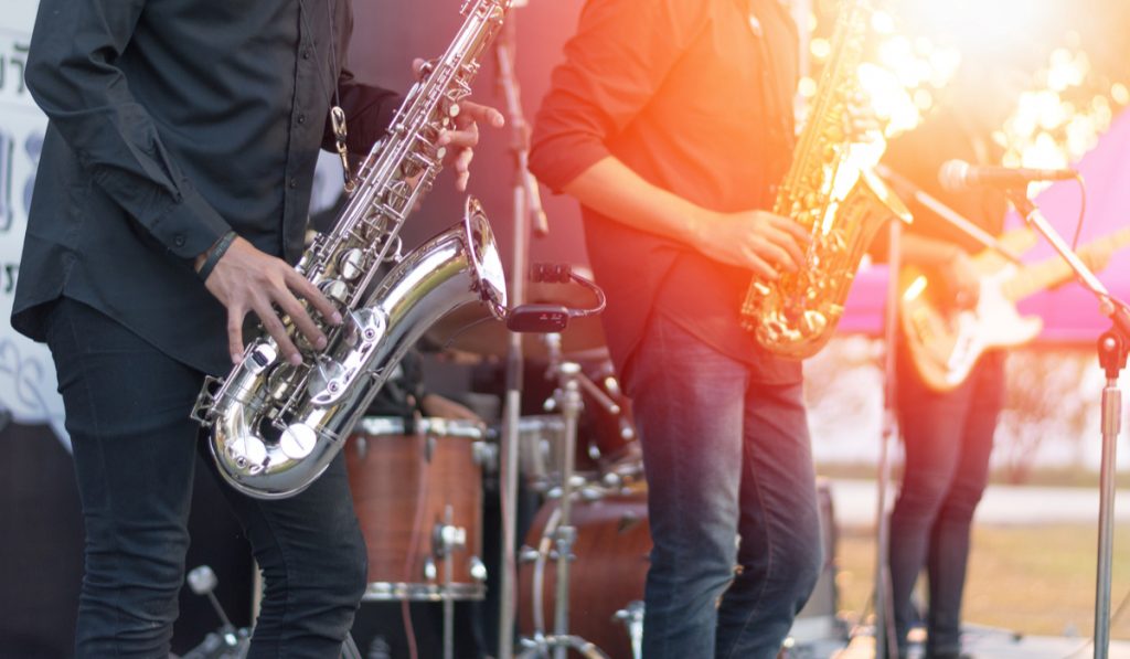 Saxophone, music instrument played by saxophonist player and band musicians on stage in fest.