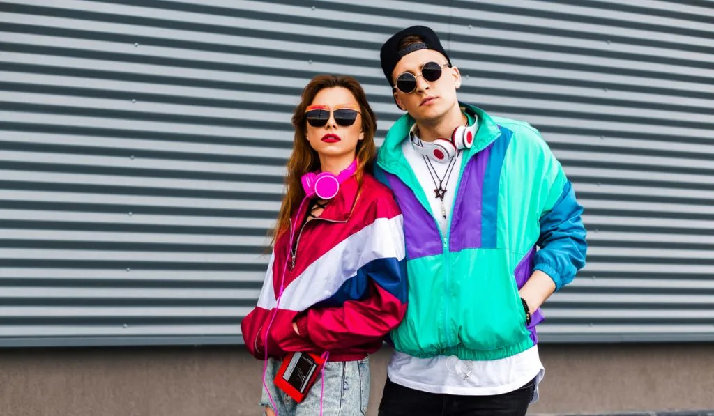 Stylish young man in a retro jacket and a girl in red and with a vintage cassette player,