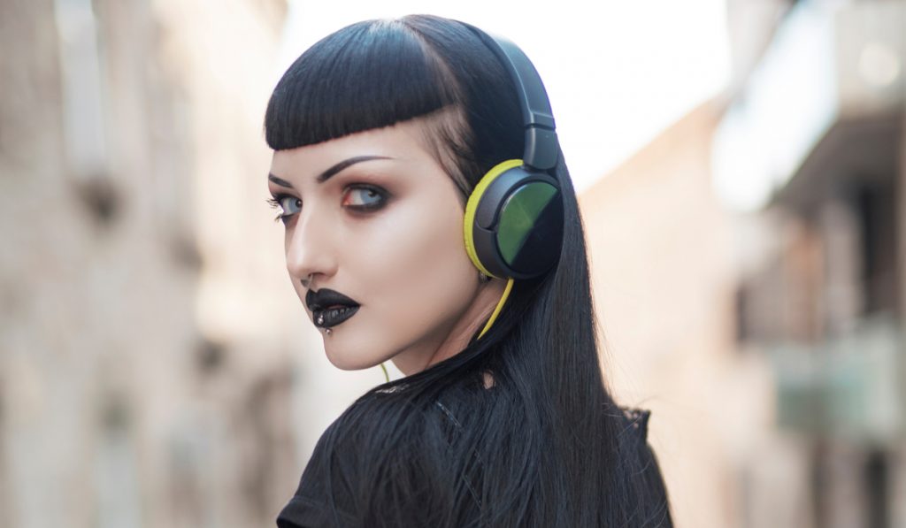 Urban goth girl listening to her favourite music over her big headphones