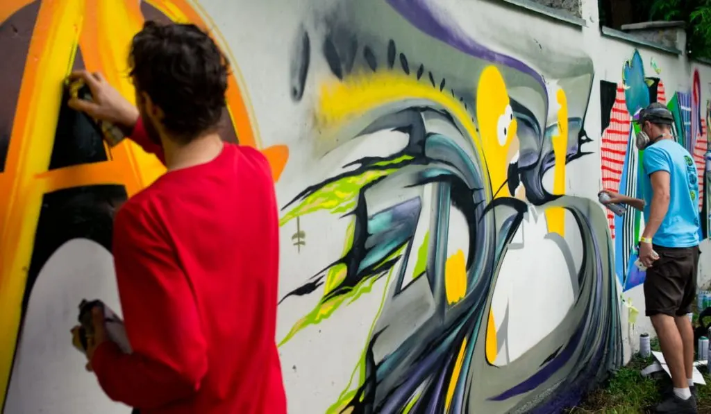 artists creating graffiti on wall 