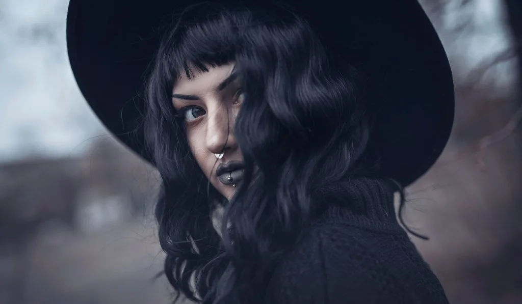 gothic girl with black hat lipstick and  nose earing