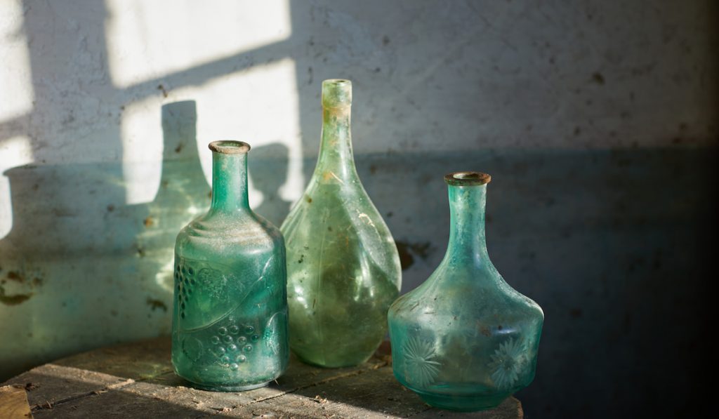 green glass vintage decanters in sunbeams
