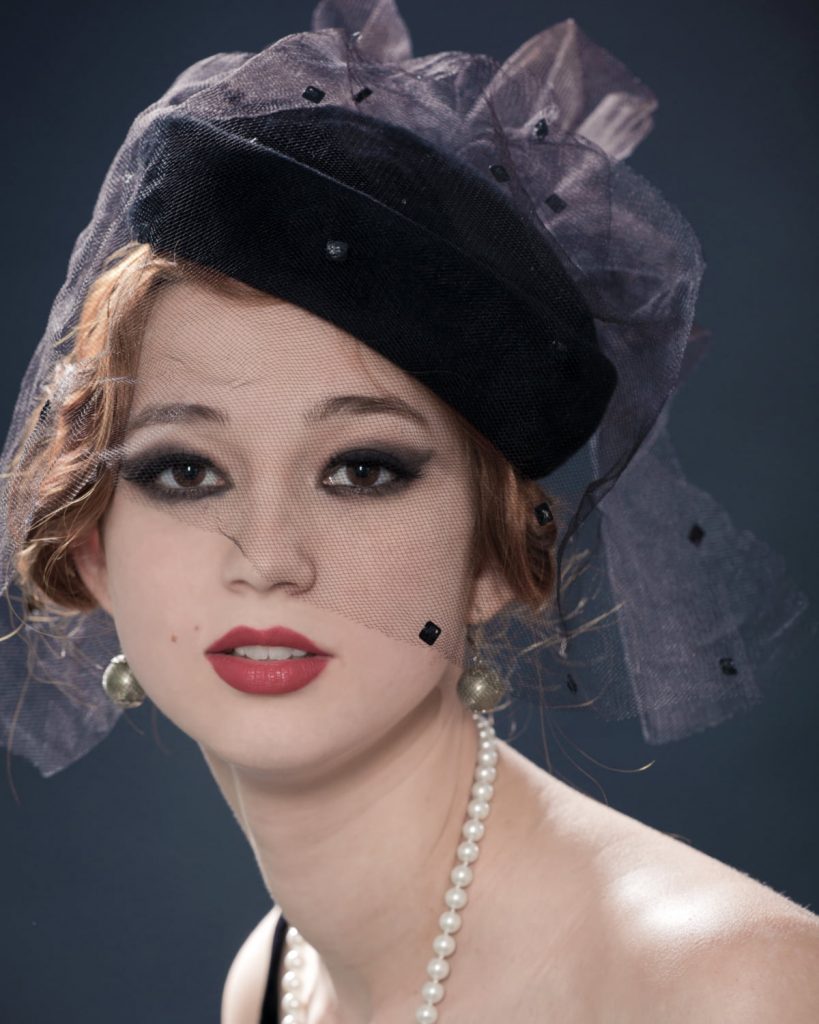 lady wearing a black pillbox hat with a lace