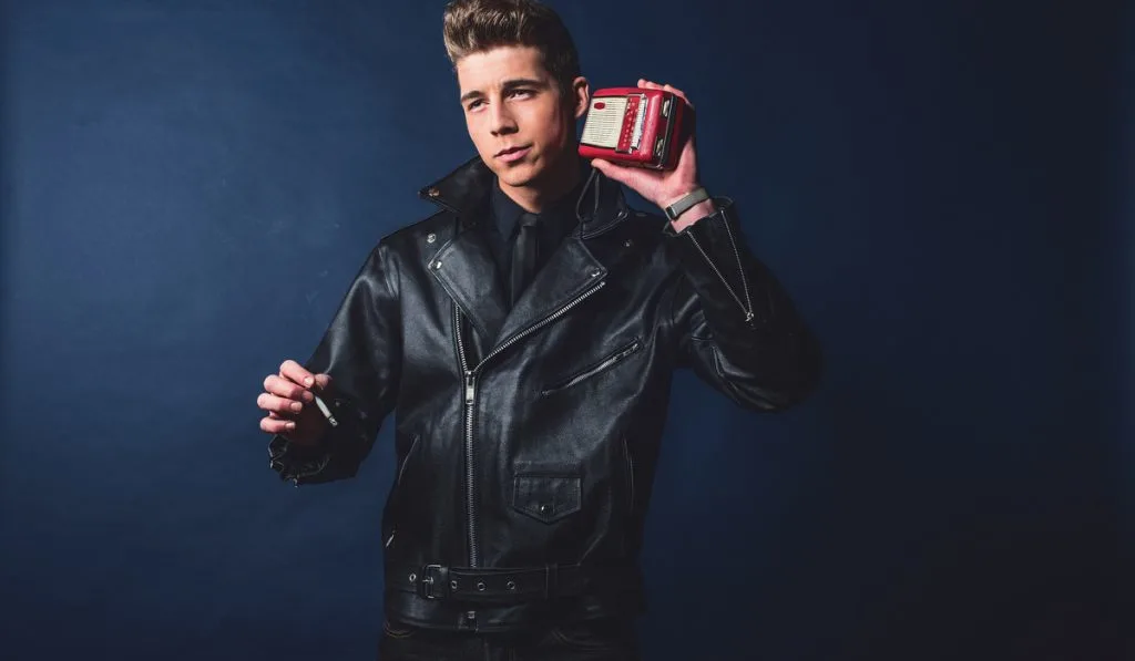 man listening to portable radio. Wearing leather jacket and jeans.