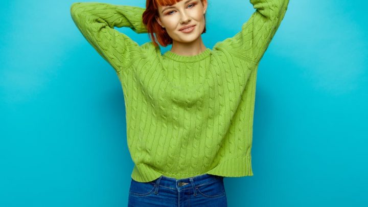 red haired woman wearing green sweater with blue denim jeans