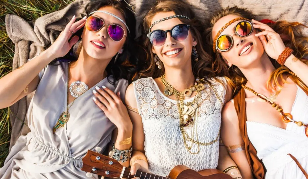 three cute hippie ladies laying on the grass watching the sunset